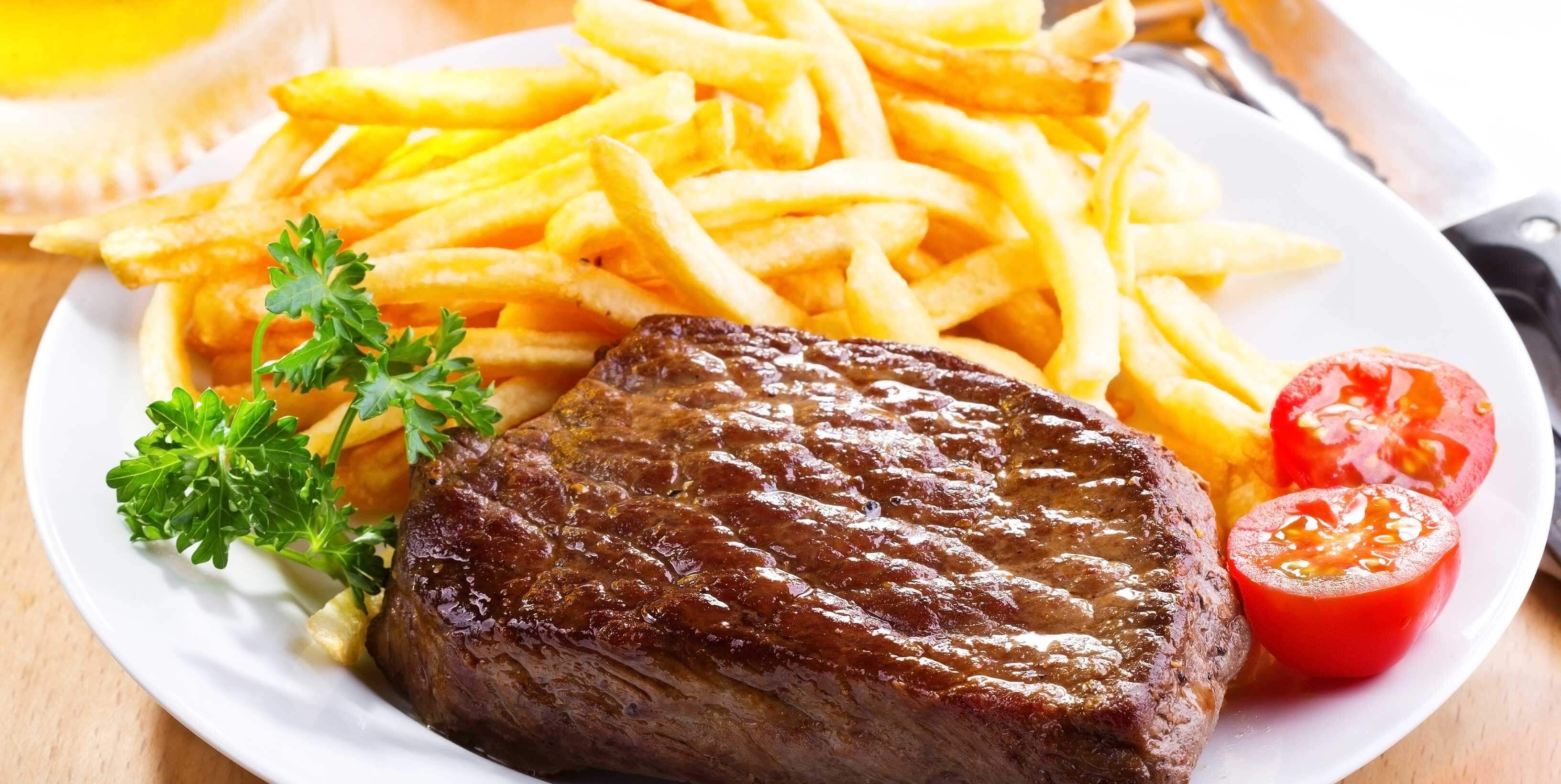 Plate of grilled steak and golden deep fried French Fries